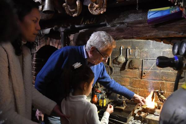 <i>Fotografía del 30 de mayo de 2025 del orfebre Juan Carlos Pallarols (c) enseñando a una niña en su taller en el barrio San Telmo, en Buenos Aires (Argentina). EFE/ Enrique Garcia Medina</i>