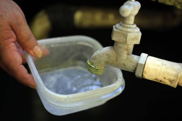 Fotografía de archivo de una persona intenta llenar un recipiente con agua. EFE/ Gustavo Amador