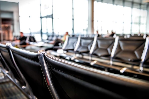 Airport interior with black trash can garbage bin in foreground and blurry bokeh background of waiting area at departure gate with nobody empty in USA