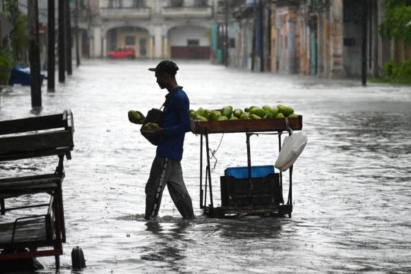<i>Un hombre vende frutas en una calle inundada de La Habana, el 29 de agosto de 2023, durante el paso de la tormenta tropical Idalia. La tormenta tropical Idalia se fortaleció hasta convertirse en huracán este martes y los meteorólogos pronostican que se volverá extremadamente peligrosa antes de tocar tierra el miércoles en Florida, Estados Unidos. (Foto de Yamil LAGE / AFP)</i>