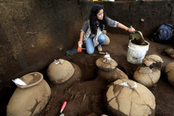 An employee of the Nicaraguan Institute of Culture (INC) worksnext to some 30 1,200-year-old pieces which were found in the surroundings of the construction site of the new National Baseball Stadium in Managua on June 20, 2017. / AFP PHOTO / INTI OCON