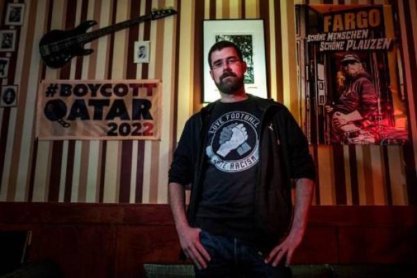 FOTO Joschik Pech, entusiasta del fútbol y portavoz del bar Fargo, posa junto a una pancarta de “Boicot Qatar 2022” en el bar Fargo de Berlín el 10 de noviembre de 2022. - Cuando Alemania inicie su campaña en la Copa Mundial de Qatar contra Japón el 23 de noviembre, el las pantallas de los proyectores en el bar de fútbol Fargo de Berlín estarán en su inusual posición enrollada. El bar, que adapta su horario habitual de apertura al horario de fútbol, ni siquiera abrirá sus puertas hasta una hora después de que finalice el partido. Fargo es uno de las docenas de bares en toda Alemania, incluidos varios en la capital de Berlín, que se comprometieron a boicotear lo que normalmente es un evento destacado en la nación loca por el fútbol. (Foto de John MACDOUGALL / AFP)