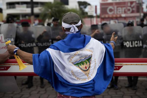 <i>Fotografía de un joven con una bandera de Nicaragua frente a Policías, en Managua (Nicaragua). EFE/Jorge Torres</i>