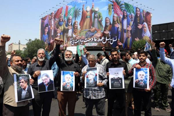 <i>Iraníes sostienen retratos de los científicos y jefes de las Fuerzas Armadas y la Guardia Revolucionaria que murieron en los ataques aéreos israelíes, durante una protesta en Teherán, Irán, el 13 de junio de 2025. EFE/EPA/ABEDIN TAHERKENAREH</i>