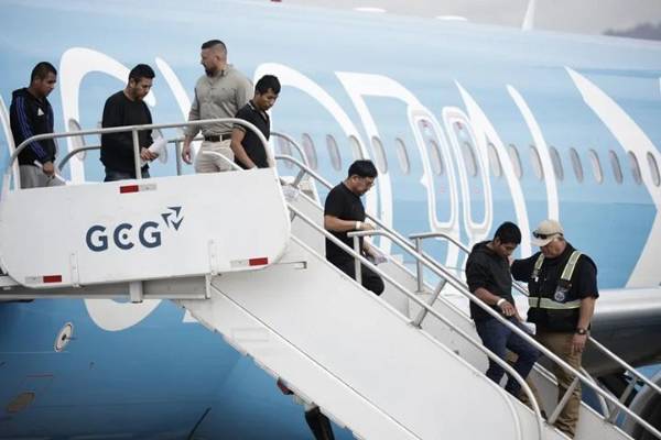 Fotografía de migrantes de distintas nacionalidades, procedentes de Estados Unidos, descienden de un avión este sábado, en el Aeropuerto Internacional Juan Santamaría, en San José (Costa Rica). (EFE/ Jeffrey Arguedas)