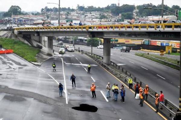 Vista de un agujero gigante en una carretera causado por el colapso de una red de drenaje por las fuertes lluvias que afectaron al país, en Villa Nueva, 15 km al sur de Ciudad de Guatemala el 14 de junio de 2022. Johan ORDÓNEZ / AFP