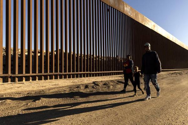 <i>Fotografía de archivo del 28 de octubre de 2022 de una familia caminando junto al muro fronterizo en Yuma, Arizona(Estados Unidos). Estados Unidos anunció este viernes la terminación de programas migratorios humanitarios de reunificación familiar para nacionales de Colombia, Cuba, Ecuador, El Salvador, Guatemala, Haití y Honduras, así como para sus familiares inmediatos, argumentando abusos de estas protecciones. EFE/EPA/ Etienne Laurent / ARCHIVO</i>