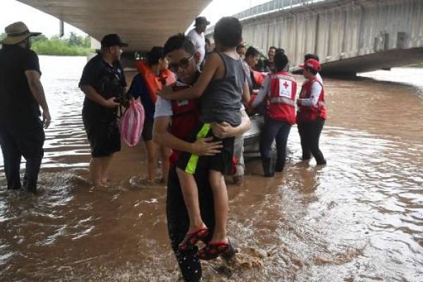 Efectivos de la cruz roja hondureña rescatan a habitantes de El Progreso, Honduras, tras el desbordamiento del río Ulúa el 24 de septiembre de 2022. - Honduras declaró alerta roja en la región noroeste del país por el azote de lluvias torrenciales que provocó la desborde de ríos, dejando al menos 13 muertos durante la última semana y más de 200 viviendas destruidas por derrumbes en la capital hondureña. (Foto por Orlando SIERRA / AFP)