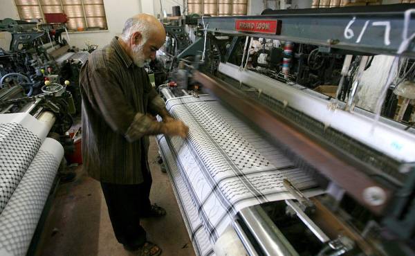 <i>Una persona trabaja junto a un telar en una fábrica textil. Imagen de archivo. EFE/Abed Al Hashlamoun</i>