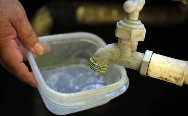 Fotografía de archivo de una persona intenta llenar un recipiente con agua. EFE/ Gustavo Amador