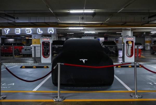 <i>Un Tesla Model Y está cubierto junto a estaciones de carga de vehículos eléctricos con sobrealimentador antes de su presentación por primera vez en Kuala Lumpur el 20 de julio de 2023. FOTO Mohd RASFAN / AFP</i>