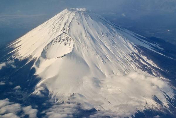 <i>Esta foto tomada el 30 de enero de 2024 muestra una vista aérea del Monte Fuji, la montaña más alta de Japón con 3.776 metros (12.389 pies), desde la ventana de un avión de pasajeros. El 13 de mayo de 2024, las autoridades japonesas anunciaron un sistema de reserva en línea para el sendero más popular del Monte Fuji que intentaba combatir el exceso de turismo en el volcán activo.Richard A. Brooks/AFP</i>