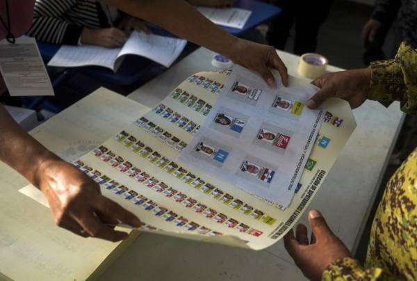 <i>Un soldado recibe una boleta de votación durante las elecciones presidenciales y legislativas en un colegio electoral en el barrio La Campanera en Soyapango, El Salvador, el 4 de febrero de 2024. El barrio La Campanera ha sido un bastión de la pandilla Barrio 18 durante décadas. FOTO CAMILO FREEDMAN / AFP</i>