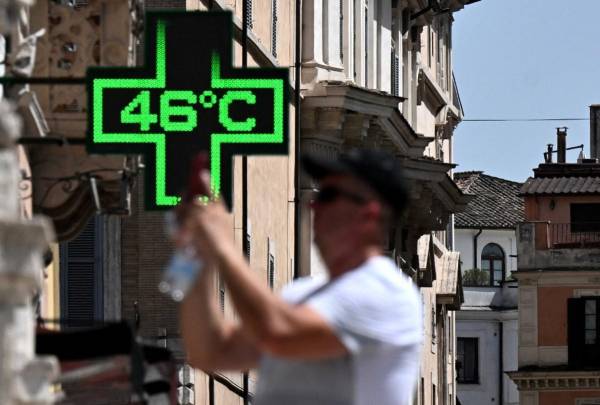 <i>Un turista toma una fotografía frente al cartel de una farmacia que indica la temperatura exterior actual de 46 grados Celsius cerca de la Scalinata di Trinita dei Monti (Plaza de España) en Roma, el 18 de julio de 2023. FOTO Tiziana FABI/AFP</i>