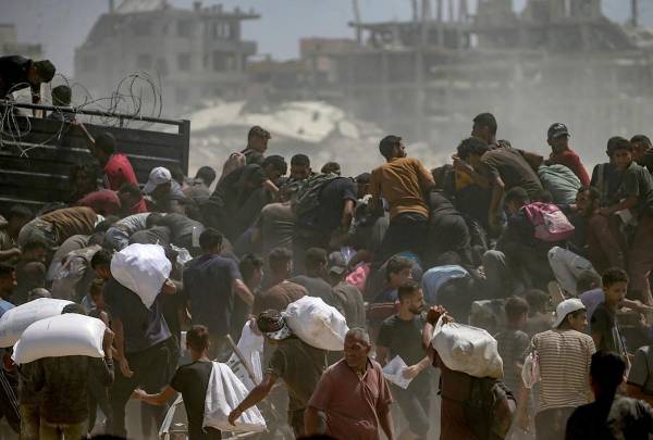 <i>Palestinos desplazados internamente intentan conseguir bolsas de harina de un camión de ayuda cerca de un punto de distribución de alimentos en Zikim, en el norte de la Franja de Gaza, el 8 de agosto de 2025. EFE/EPA/MOHAMMED SABER</i>