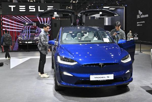 <i>Los visitantes miran un Tesla Model X durante una vista previa para la prensa del Salón de Movilidad de Seúl 2023 en la sala de exposiciones KINTEX en Goyang el 30 de marzo de 2023.Jung Yeon-je / AFP</i>