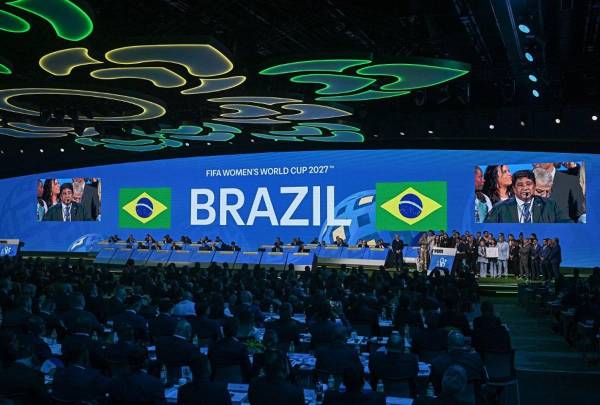 <i>El presidente de la Asociación Brasileña de Fútbol, Ednaldo Rodrigues, está rodeado por su delegación mientras pronuncia un discurso después de que Brasil gane su candidatura para albergar la Copa Mundial Femenina de 2027 durante el 74º Congreso de la FIFA en Bangkok el 17 de mayo de 2024. FOTO Lillian SUWANRUMPHA / AFP</i>