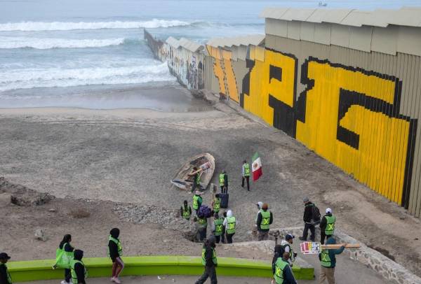 <i>Miembros de Border Angels y migrantes se manifiestan en la frontera entre Estados Unidos y México como parte del Día Internacional del Migrante en Playas de Tijuana, estado de Baja California, México, el 18 de diciembre de 2023. FOTO Guillermo Arias/AFP</i>