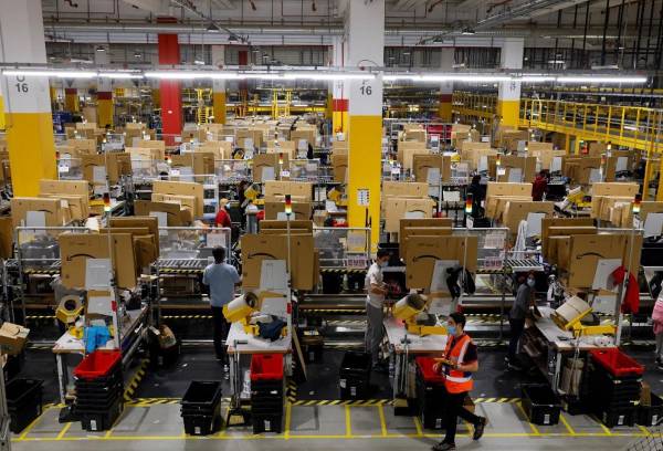 <i>Empleados trabajan en el centro de Amazon en Bretigny-sur-Orge, el 14 de diciembre de 2021. La agencia de protección de datos de Francia dijo el 23 de enero de 2024 que había multado a la unidad de almacenes francesa de Amazon con 32 millones de euros (34,9 millones de dólares) por un sistema de vigilancia excesivamente intrusivo para realizar un seguimiento del desempeño del personal. FOTO THOMAS SAMSON / AFP</i>