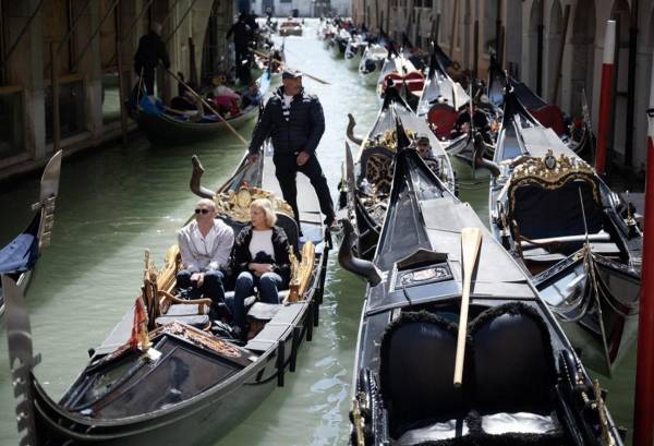 <i>Un gondolero navega con dos clientes cerca de la Plaza de San Marcos en Venecia, el 25 de abril de 2024. La nueva estrategia para reducir el número de turistas que visitan este lugar declarado Patrimonio de la Humanidad por la UNESCO exige que los excursionistas paguen un billete de cinco euros para entrar en el histórico centro de la ciudad y comenzará el 25 de abril. FOTO MARCO BERTORELLO/AFP</i>