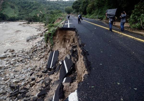 La gente pasa por parte de una carretera que fue arrasada en la comunidad del Kilómetro 42, cerca de Acapulco, estado de Guerrero, México, tras el paso del huracán Otis, el 25 de octubre de 2023 .RODRIGO OROPEZA / AFP