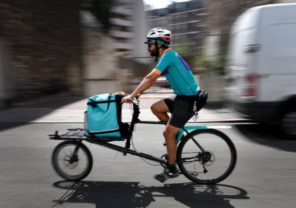 <i>Un ciclista que trabaja para el servicio de entrega de alimentos Deliveroo va en bicicleta para entregar un pedido en Saint-Ouen, en las afueras de París. FOTO GERARD JULIEN / AFP</i>