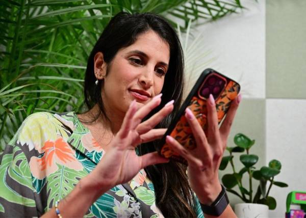 <i>La entrenadora de citas Sabrina Zohar revisa su teléfono celular desde un estudio en su casa en Carlsbad, California, el 6 de febrero de 2024. FOTO FREDERIC J. BROWN / AFP</i>