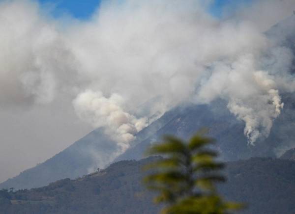 <i>El humo surge de los incendios forestales en las laderas del volcán de Agua, visto desde Villa Nueva, Guatemala, el 22 de febrero de 2024. Un voraz incendio forestal arrasa las laderas del inactivo volcán de Agua, cerca de la capital de Guatemala, sin víctimas o evacuaciones reportadas hasta el momento. FOTO Johan ORDÓÑEZ / AFP</i>