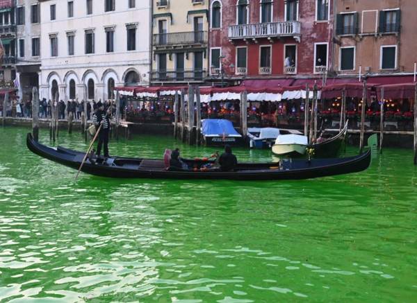 <i>Una góndola navega por el Gran Canal después de que activistas de Extinction Rebellion (XR) vertieran fluoresceína cerca del puente de Rialto en Venecia para hacer que el agua fuera fluorescente durante una protesta contra el 'fracaso' de la COP28 sobre el clima. FOTO Marco SABADÍN / AFP</i>
