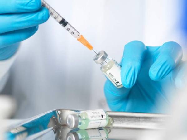 Close up of doctors hands preparing a vaccine to inject patient