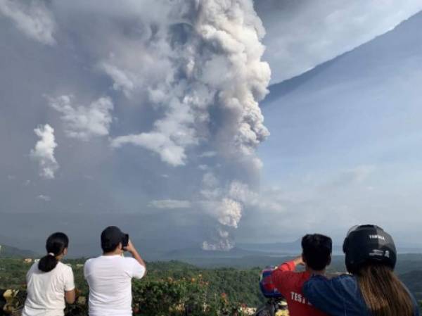 People take photos of a phreatic explosion from the Taal volcano as seen from the town of Tagaytay in Cavite province, southwest of Manila, on January 12, 2020. (Photo by Bullit MARQUEZ / AFP)