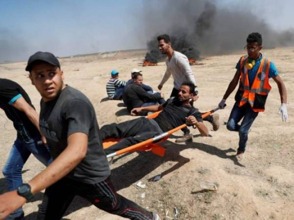 Palestinos cargan un protestante herido durante la marcha contra el Ejército de Israel en la frontera de la Franja de Gaza. AFP PHOTO / Thomas COEX