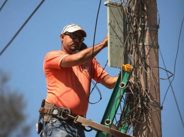 Un integrante de las cuadrillas de la estatal realiza cortes a morosos. (Foto: laprensa.hn).