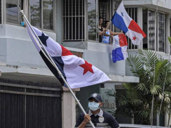 A police officer wearing a mask carries a Panamanian national flag as members of the force cheer up the neighbourhood with dances and songs during a lockdown to help contain the COVID-19 novel coronavirus pandemic, in Panama City on June 28, 2020. - The total number of global COVID-19 infections has now surpassed 10 million, according to an AFP tally at 0930 GMT on Sunday based on official sources, with at least 498,779 people killed worldwide so far according to the count. (Photo by Luis ACOSTA / AFP)