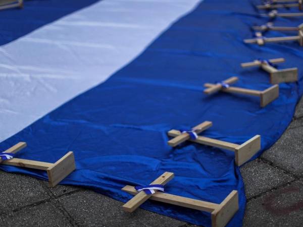 <i>Se ven cruces encima de una bandera de Nicaragua durante una manifestación para conmemorar el Día Nacional de la Paz de Nicaragua, que se celebra en el país el 19 de abril. FOTO José Cordero / AFP</i>