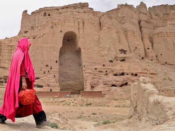 Una mujer afgana pasa frente a las ruinas de las antiguas estatuas de Buda en la ciudad de Bamiyán, el 1 de agosto de 2010. Foto: SHAH MARAI|AFP