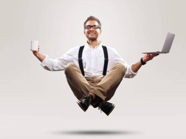 Young man is soaring in the air with a Cup of coffee and a laptop