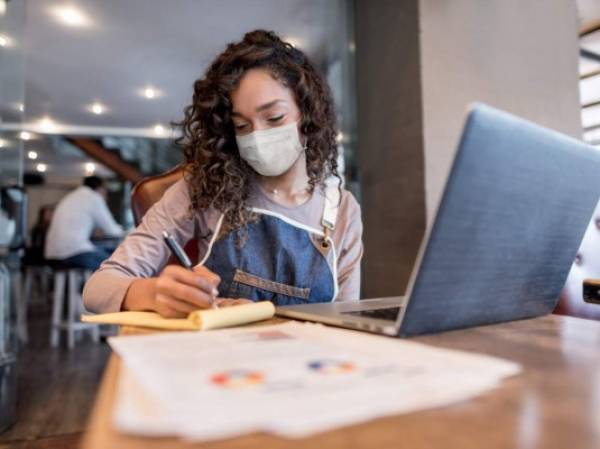 Business manager doing the books at a restaurant wearing a facemask to avoid coronavirus â pandemic lifestyle concepts