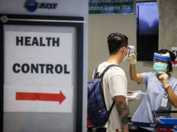 A health official checks the temperature of an incoming passenger during a health assessment at a checkpoint for people flying in from a list of countries and territories that include China, Hong Kong, Macau, South Korea, Iran and Italy, as a precautionary measure against the spread of the COVID-19 coronavirus at Suvarnabhumi Airport in Bangkok on March 9, 2020. (Photo by VIVEK PRAKASH / AFP)