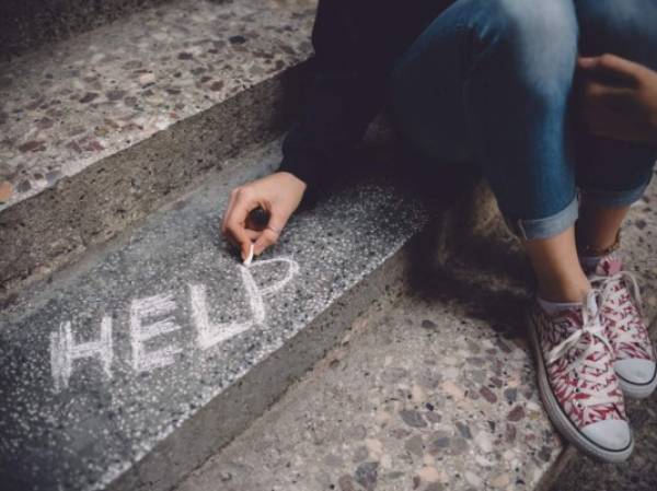 Teenage girl sitting on a staircase outside feeling depressed