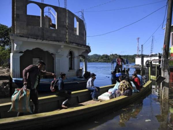 Residentes viajan en bote por una calle inundada de la comunidad indígena Comunidad Campur, Guatemala, el 10 de diciembre de 2020. - La comunidad indígena de Campur en el norte de Guatemala se ha convertido en una laguna luego del paso de los huracanes Eta e Iota, que dejaron 160 muertos y desaparecido en el país. (Foto de Johan ORDONEZ / AFP)