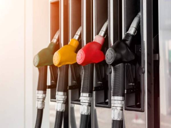 Green, yellow, red and black fuel pistols on fuel station. Closeup.