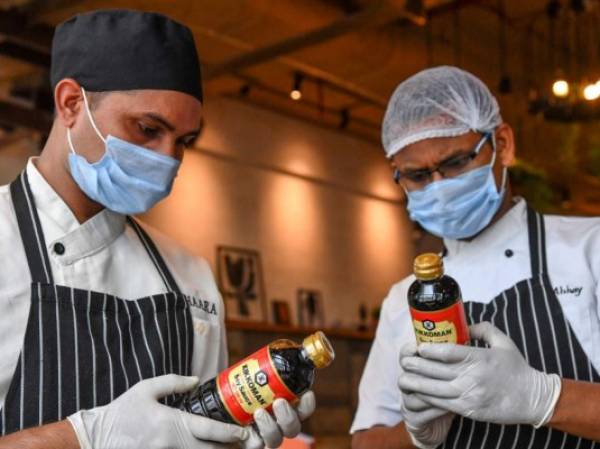 In this picture taken on July 16, 2021 chefs check freshly arrived bottles of Kikkoman Soy Sauce at the Ishaara restaurant in Mumbai. - Every dish tastes better with a dash of soy sauce, even dessert: that's the ambitious pitch of Japanese food giant Kikkoman, hoping to persuade Indians to use it in curries, sweets and everything in between. (Photo by Indranil MUKHERJEE / AFP) / TO GO WITH: India-Japan-Food-Kikkoman, FOCUS by Ammu KANNAMPILLY