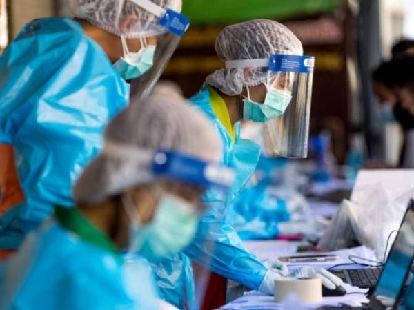 Medical workers take details from people, as hospitality and tourism workers are tested for the Covid-19 coronavirus on Khao San Road, in Bangkok on January 6, 2022. (Photo by Jack TAYLOR / AFP)