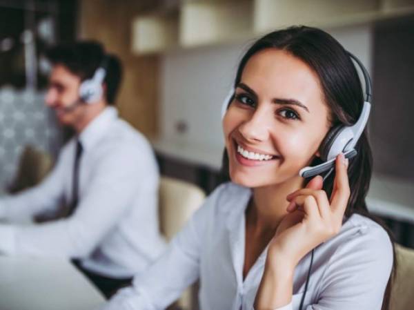 How can I help you? Beautiful call center workers in headphones are working at modern office.