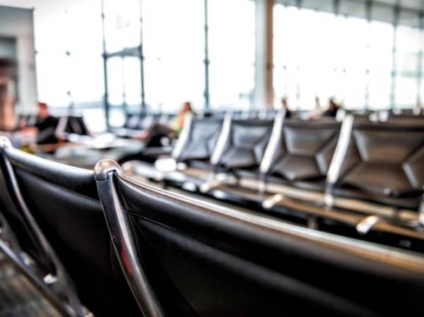 Airport interior with black trash can garbage bin in foreground and blurry bokeh background of waiting area at departure gate with nobody empty in USA