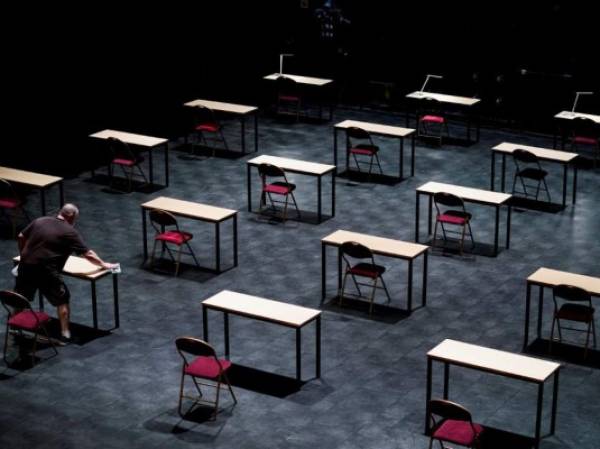 A man disinfects tables in an empty exam room at the 'Ancienne Belgique' (AB) concert hall in Brussels, on June 2, 2020 as Belgium eases lockdown measures taken to curb the spread of the COVID-19 (the novel coronavirus). (Photo by Kenzo TRIBOUILLARD / AFP)