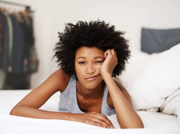 Portrait of a young woman waking up in bed and looking unhappy