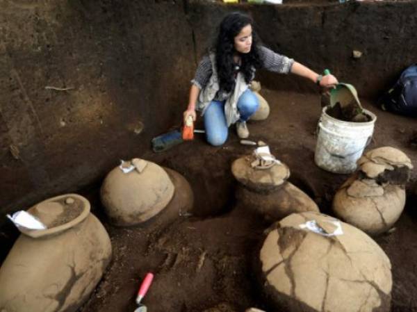 An employee of the Nicaraguan Institute of Culture (INC) worksnext to some 30 1,200-year-old pieces which were found in the surroundings of the construction site of the new National Baseball Stadium in Managua on June 20, 2017. / AFP PHOTO / INTI OCON