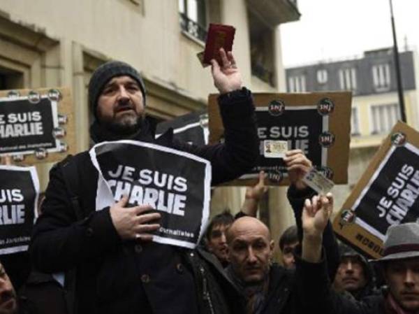 Un grupo de periodistas muestra sus carnés de prensa durante el minuto de silencio que observaron por la matanza de Charlie Hebdo. (Foto: AFP).